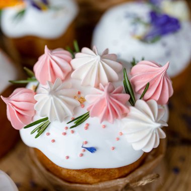 Ortodoks Paskalya 2021. Pasta dekorasyonu. Beyaz kremalı kekler, pembe ve beyaz kremayla süslenmiş, çiçekler ve doğal ahşap arka planda bitkiler. Paskalya kartı.