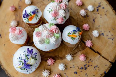 Ortodoks Paskalya 2021. Pasta dekorasyonu. Beyaz kremalı kekler, pembe ve beyaz kremayla süslenmiş, çiçekler ve doğal ahşap arka planda bitkiler. Paskalya kartı.