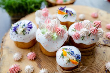 Ortodoks Paskalya 2021. Pasta dekorasyonu. Beyaz kremalı kekler, pembe ve beyaz kremayla süslenmiş, çiçekler ve doğal ahşap arka planda bitkiler. Paskalya kartı.