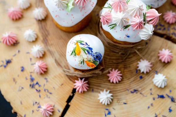 Ortodoks Paskalya 2021. Pasta dekorasyonu. Beyaz kremalı kekler, pembe ve beyaz kremayla süslenmiş, çiçekler ve doğal ahşap arka planda bitkiler. Paskalya kartı.