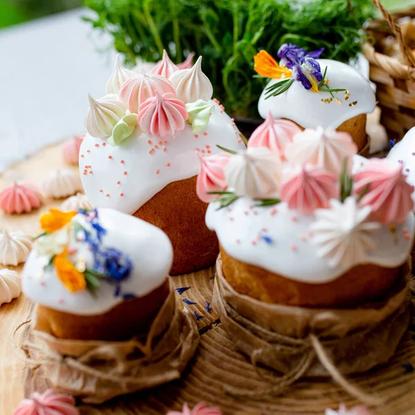 Ortodoks Paskalya 2021. Pasta dekorasyonu. Beyaz kremalı kekler, pembe ve beyaz kremayla süslenmiş, çiçekler ve doğal ahşap arka planda bitkiler. Paskalya kartı.