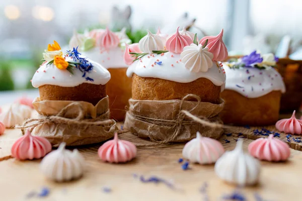 Ortodoks Paskalya 2021. Pasta dekorasyonu. Beyaz kremalı kekler, pembe ve beyaz kremayla süslenmiş, çiçekler ve doğal ahşap arka planda bitkiler. Paskalya kartı.