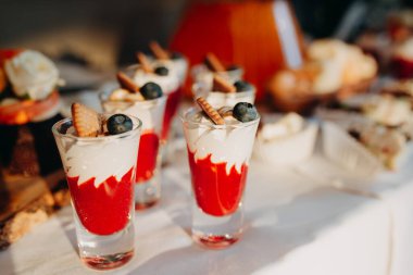 Düğün menüsü. Beyaz bir masa örtüsü ve ahşap bir kulübede yaban mersini ve waffle külahlı tatlı çilekli düğün tatlısı servis ediyorum..