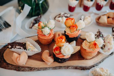 Düğün menüsü. Çikolata. Tahta servis tahtasına güllerle düğün pastası servis etmek. Düğün yemekleri..