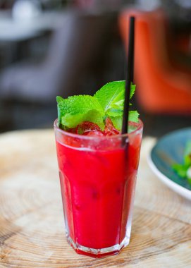Yaz içkileri. Buzlu karpuz renginde meyveli meyve püresi ve arka planda bulanıklık ve metin için bir yer olan doğal ahşap arka planda bir bardakta Melissa..