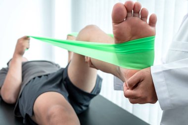 Atletizm hastasının yaralı bacağını tedavi eden fizyoterapist, klinikte rehabilitasyon tedavisi gören doktor..
