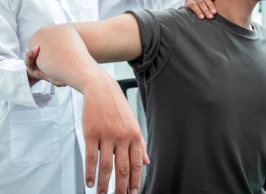 Spor hastalarının yaralı kollarını tedavi eden, esneme ve egzersiz yapan, klinikte acı rehabilitasyonu yapan kadın fizyoterapist.