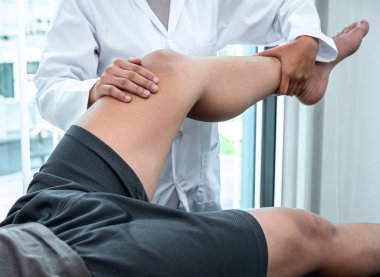 Kadın fizyoterapist, hastanın yaralı bacağını tedavi ediyor, rehabilitasyon tedavisi uyguluyor, klinikte acı çekiyor..