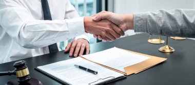 Erkek avukat, iyi bir müzakere işbirliği toplantısı sonrasında müvekkille tokalaşıyor..