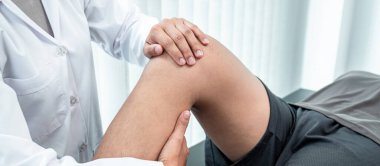 Atletizm hastasının yaralı bacağını tedavi eden fizyoterapist, klinikte rehabilitasyon tedavisi gören doktor..