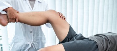 Kadın fizyoterapist, hastanın yaralı bacağını tedavi ediyor, rehabilitasyon tedavisi uyguluyor, klinikte acı çekiyor..