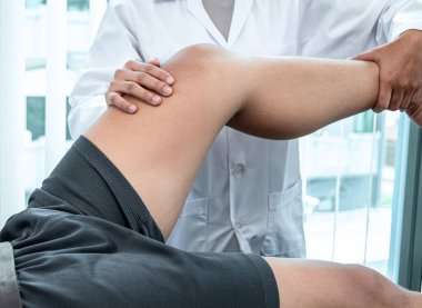 Atletizm hastasının yaralı bacağını tedavi eden fizyoterapist, klinikte rehabilitasyon tedavisi gören doktor..