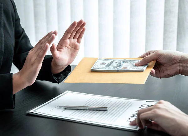 Business woman refusing receive bribe money in the envelope of their partner to give success the deal contract in a corruption scam, illegal and dishonest.