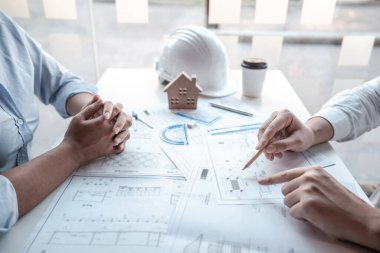 Mimarlar veya mühendislik ekibi, modern ofisteki tasarım ve model ev üzerine yeni mimari projeler planlayan nesneler, araçlar ve inşaat çizimleri üzerinde danışmanlık ve analiz yapıyor..