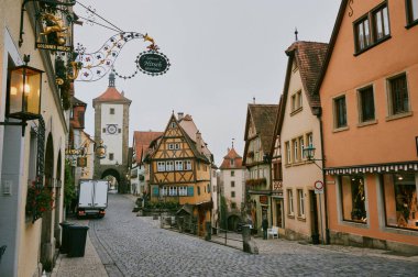 Rothenburg ob der Tauber 'deki Cobblestone caddesinde yarım ahşap evler, bir saat kulesi ve Goldener Hirsch için işlenmiş demir levhalar vardı.