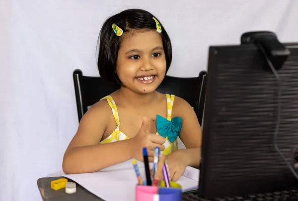 オンライン授業のためにデスクトップコンピュータの前に笑顔で座っているインドの女の子の子供 — ストック写真