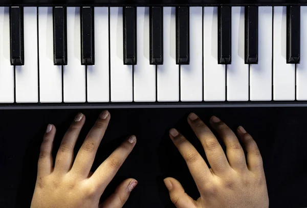 Top view of piano or keyboard with human hand in black background