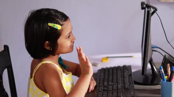 ein indisches Mädchen mit lächelndem Gesicht sitzt vor dem Desktop-Computer