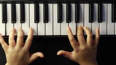 İnsan eli siyah arkaplanda piyano veya klavye çalmanın üst görünümü