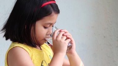 Bardaktan su içen Hintli bir kızın yan açısı.