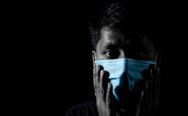 Siyah arka planda cerrahi burun maskesi takan Hintli bir Asyalının basit bir fotoğrafı.