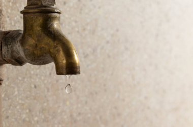 Pirinçten yapılmış metal bir musluğun yan görünüşü, yerel odada su damlaları.