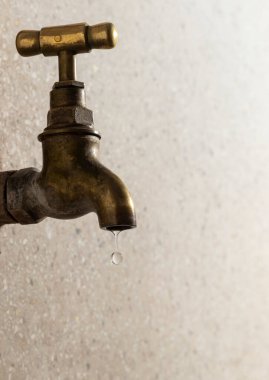 Pirinçten yapılmış metal bir musluğun yan görünüş portresi, ev ortamında su damlası.