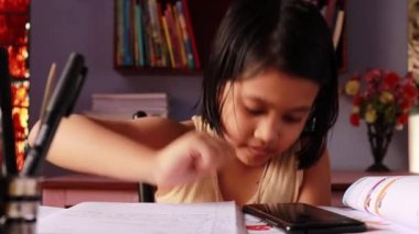 Hintli bir kız çocuğu günlük kıyafetlerle geziyor ve ders çalışıyor.