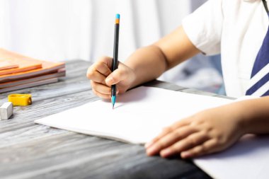 Okul üniforması giyen, kalemle not alan Hintli bir çocuğun eline odaklan.