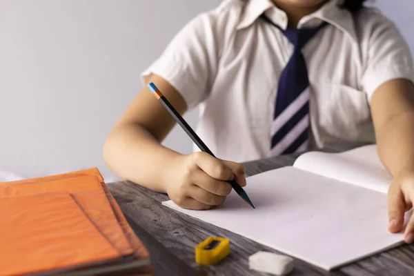 学校の制服を着てノートに鉛筆で書くインドの子供の手に選択的な焦点 — ストック写真