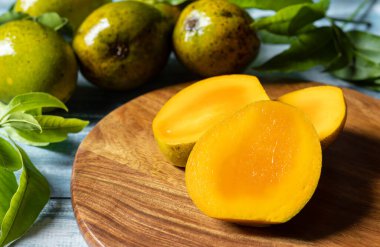 Olgun mango dilimlerine, tahta kesme tahtalarına, mangolara ve ahşap masa yapraklarına odaklan.