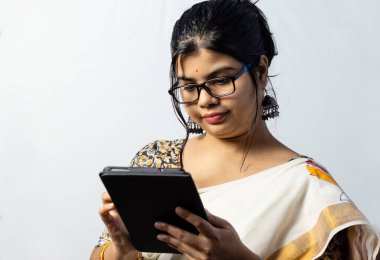 Beyaz arka planda, sarili Hintli bir ofis kadını tablet üzerinde çalışıyor.