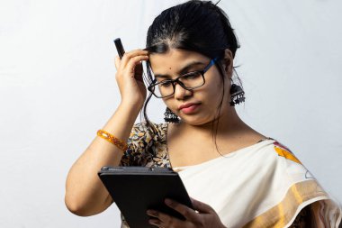 Beyaz arka planda, sarili Hintli bir ofis kadını tablet üzerinde çalışıyor.