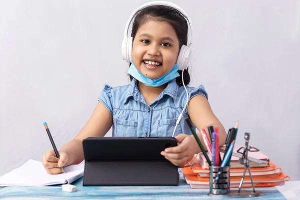 白い背景にタブレットやヘッドフォンでオンラインクラスに出席かなりインドの女の子 — ストック写真