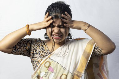 Beyaz arka planda sari giymiş, başı ağrıyan bir Hintli kadın var.