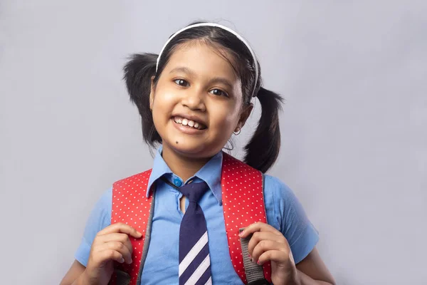 Portret Uśmiechniętej Indyjskiej Uczennicy Niebieskim Mundurze Szkolnym Czerwoną Torbą Szarym — Zdjęcie stockowe
