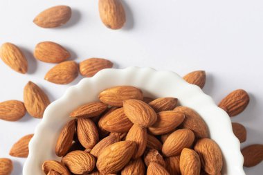 Beyaz arka planda beyaz bir kâsede badem fıstığının üst görüntüsünü kapat