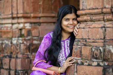 Mor giyinmiş güzel bir Hintli kadının portresi. Batı Bengal 'in teras tapınağında gülümsüyor.