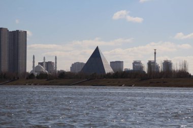 Nur-Sultan, Kazakistan - 22 Nisan 2021. Ishim Nehri (Eil) boyunca Barış ve Uzlaşma Sarayı 'nın (Piramit) manzarası)
