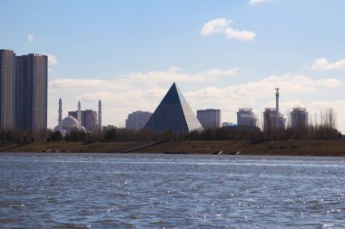 Nur-Sultan, Kazakistan - 22 Nisan 2021. Ishim Nehri (Eil) boyunca Barış ve Uzlaşma Sarayı 'nın (Piramit) manzarası)
