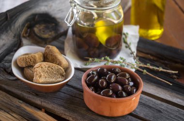 Kavanoz, zeytin, rusk ve ahşap arka planda bir şişe zeytinyağı dolu seramik kap..