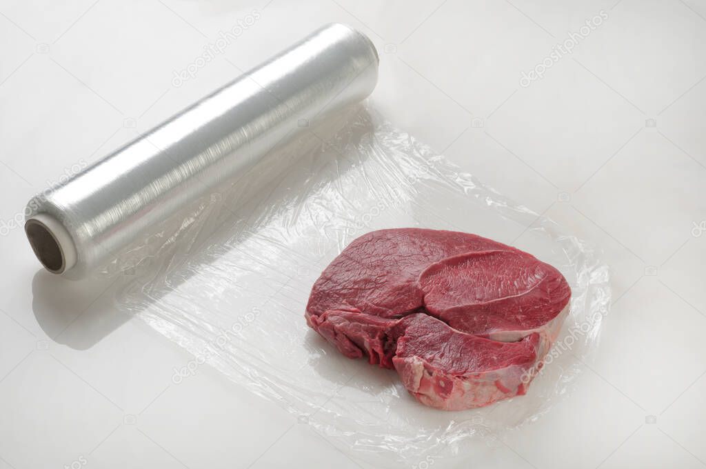 Piece of meat wrapped in cling wrap for protection.