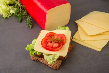 Domates dilimleriyle süslenmiş kepekli tost ekmeğine bir dilim edam peyniri..