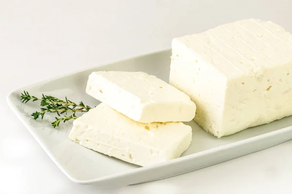 Geleneksel feta peyniri ahşap fıçılara dönüşüyor ve üçgen şeklinde kesiliyor. Kesme yolu.