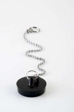 Lavabo ya da beyaz arka planda zincirli banyo giderleri için izole edilmiş siyah kauçuk tıpa. Seçici odak. 