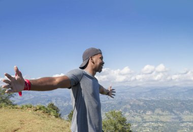 Yarım vücut görüşü, şapkalı ya da şapkalı, geniş kolları olan, özgür bir genç adamın Dominik Cumhuriyeti 'nin tropikal bir manzarasında doğaya ve saf havaya baktığı yönünde.