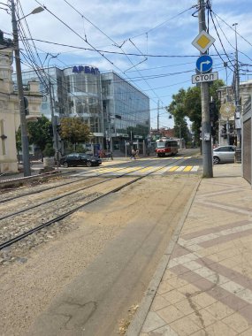 Geleneksel tramvayların klasik manzarası, sabah vakti şehir caddesi. Kablolar sarkıyor. Tarihi Binalar. Dar yollar.