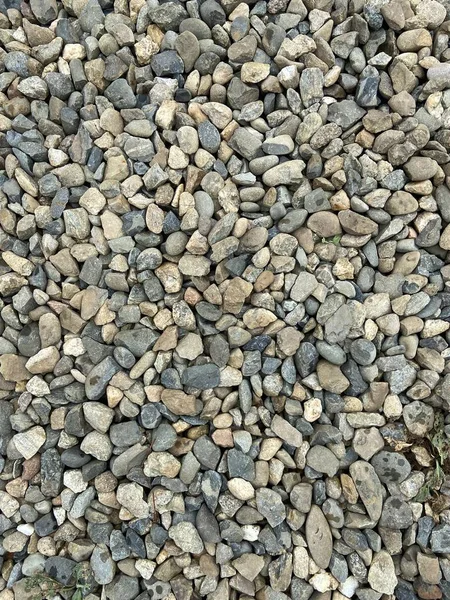 Gravel stones are scattered.  The road is not smooth.  Natural minerals.  Asphalt laying.  Plants through the sidewalk.  Landscape at home