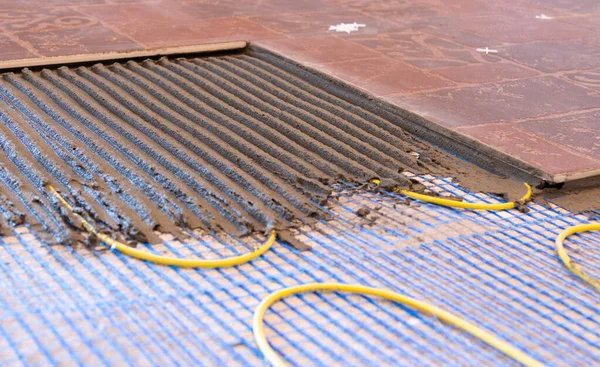 Pemasangan lantai yang hangat dari kabel. sistem pemanas listrik dengan ubin keramik dan lapisan semen Stok Gambar