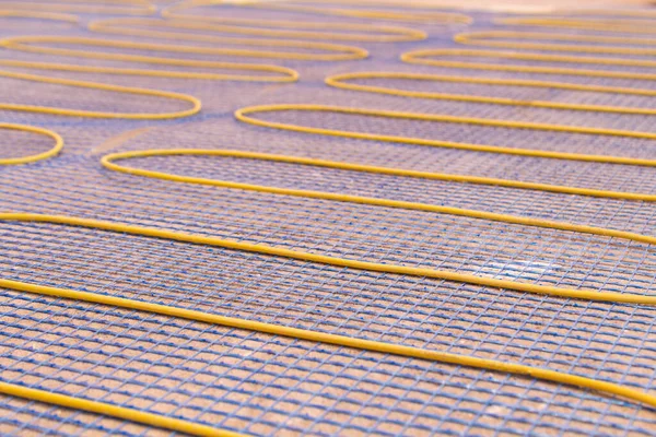 Electric underfloor heating, yellow cable on cement floor. Repair and construction, the concept of a cozy warm home.